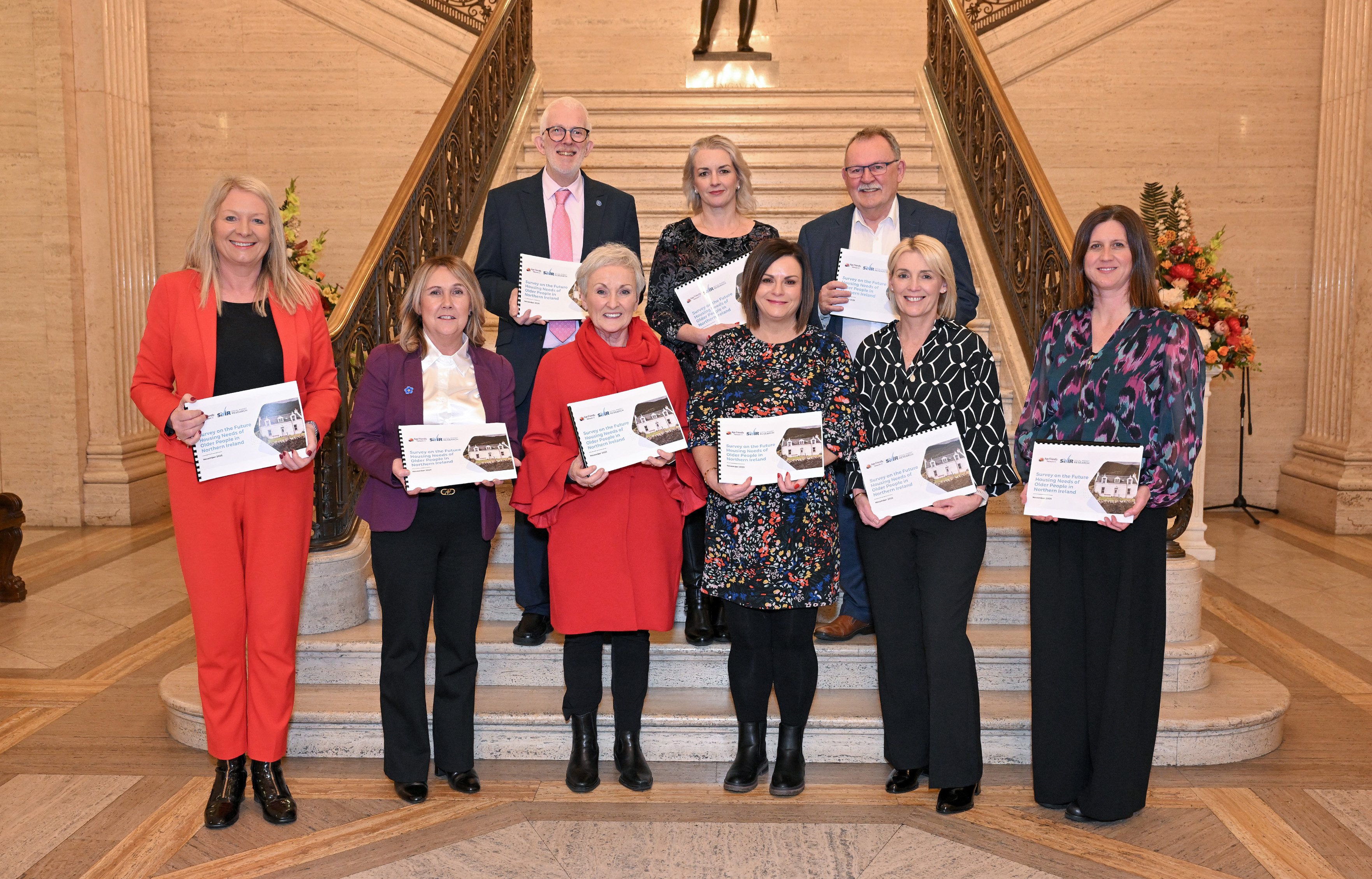 group holding reports standing on the stairs inside Stormont