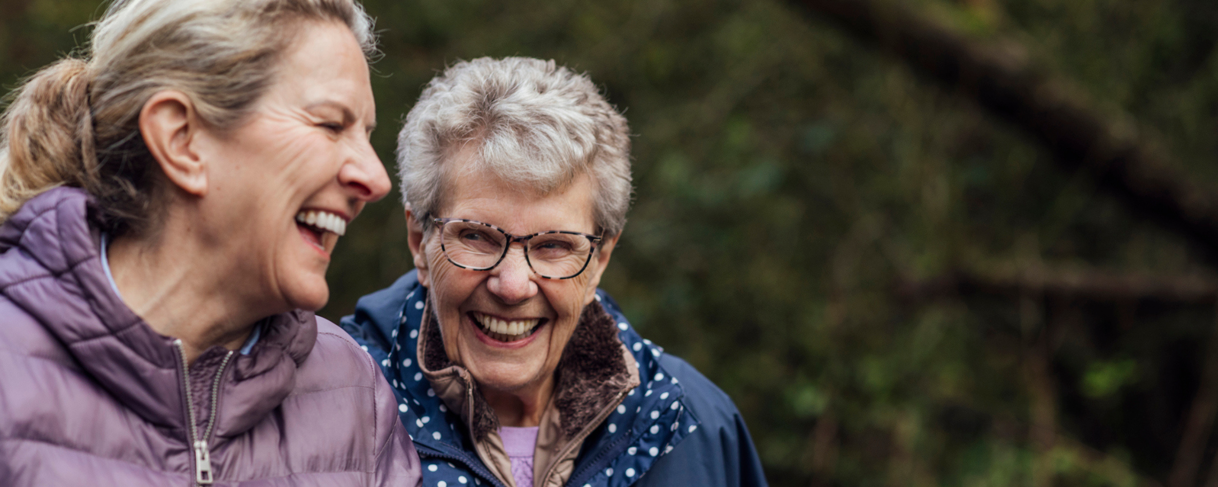 an older women and younger woman smiling outside