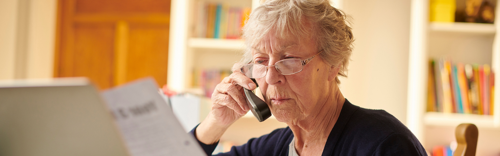 Older woman on the phone looking at a bill